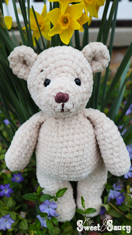 tan crochet teddy in the flowers